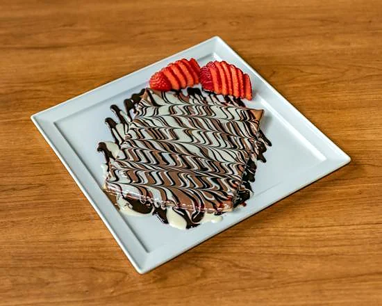 Nutella crepe with chocolate drizzle and strawberries